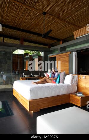 Costa Rica,osa peninsula,donna nel letto del suo design contemporaneo suite dell'ecolodge Kura ville di design Foto Stock