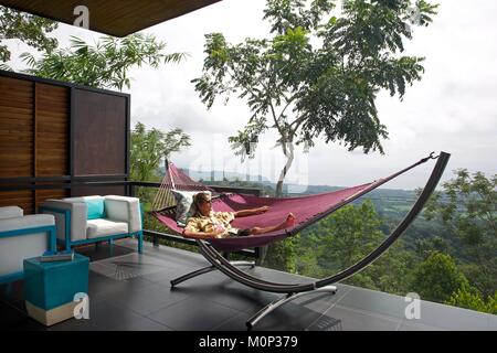 Costa Rica,osa peninsula,l uomo nella sua amaca in terrazza di un contemporaneo design suite nell'ecolodge Kura ville design,nel mezzo della foresta Foto Stock