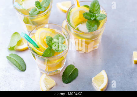 Iced dolce limone tè alla menta in bicchieri freddi su grigio chiaro tavolo, ristoro deliziosa bevanda estiva Foto Stock