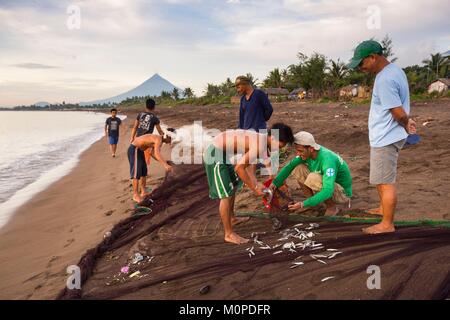 Filippine,Luzon,Albay provincia,Tiwi,pescatori portando una Tutina in rete sulla spiaggia con il vulcano Mayon nella massa posteriore Foto Stock