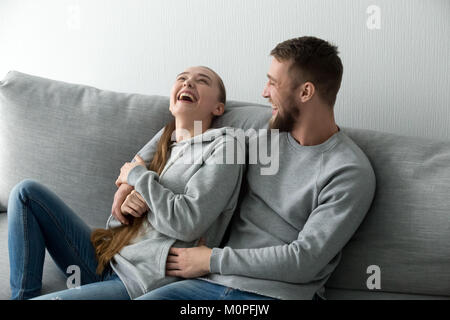 Coppia giovane avendo divertimento ridere in un momento di relax a casa sul lettino Foto Stock