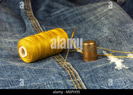 Il denim è un rocchetto di filo, ago e ditale Foto Stock