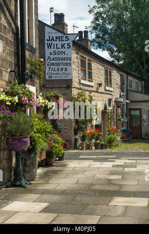 Piccolo angolo di Baildon storico con il pittoresco pietra, soleggiato cottages, fiori colorati nelle piantatrici & ghost segno sulla parete - West Yorkshire, Inghilterra, Regno Unito. Foto Stock