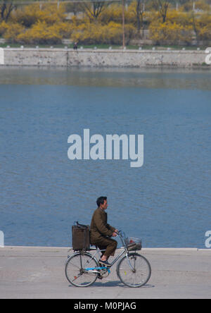 Corea del Nord uomo in bicicletta lungo il fiume Taedong, Provincia di Pyongan, Pyongyang, Corea del Nord Foto Stock