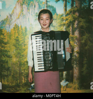 Polaroid di un sorridente nord coreano cameriera di suonare la fisarmonica, Provincia di Pyongan, Pyongyang, Corea del Nord Foto Stock