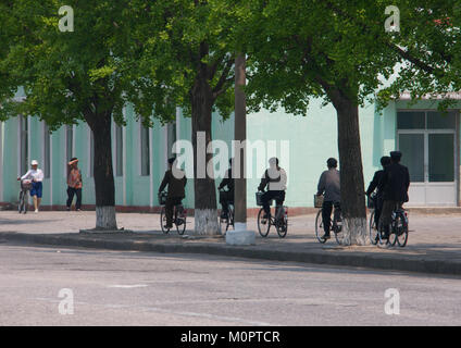 Nord Coreani equitazione biciclette sotto gli alberi, Nord provincia Hwanghae, Kaesong, Corea del Nord Foto Stock