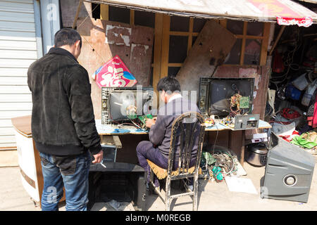 Marzo 2014 - Qingdao, Cina - un uomo è la riparazione di un vecchio televisore catodico nel quartiere povero di Shandongtou Foto Stock