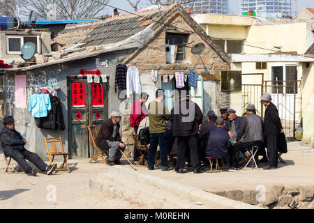 Marzo 2014 - Qingdao, Cina - un gruppo di uomini le carte da gioco nel quartiere povero di Shandongtou Foto Stock