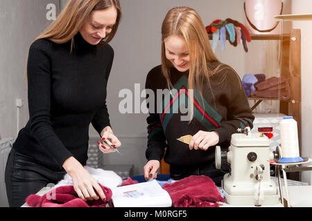 Due giovani donne furriers stanno discutendo di come propriamente tagliato pelliccia naturale per rendere una donna di pelliccia. Il processo per la fabbricazione di una donna di pelliccia Foto Stock