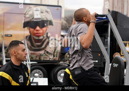 Il personale Sgt. Frank Keffales, un espositore con il Mobile presentano Company, Fort Knox, Kentucky, conta di pull up per uno studente presso l'esperienza GoArmy zona durante il 2018 U.S. Esercito ciotola All-American settimana al di fuori dell'Alamodome in San Antonio, Texas, 5 gennaio 2018. L'esercito zona esperienza dimostra l impegno dell esercito in America a favore della gioventù illustrando diversi aspetti nella vita militare. Foto Stock