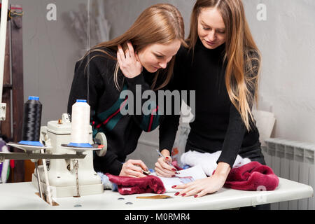 Due giovani donne furriers stanno discutendo di come propriamente tagliato pelliccia naturale per rendere una donna di pelliccia. Il processo per la fabbricazione di una donna di pelliccia Foto Stock