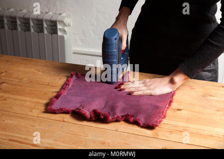 Il processo per la fabbricazione di una donna di pelliccia. Un close-up di una giovane donna pellicciaio asciuga una speciale macchina con pelliccia naturale per la realizzazione di una donna di pelliccia. Foto Stock