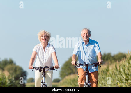 Coppia senior di guardare avanti con fiducia mentre bicyc equitazione Foto Stock