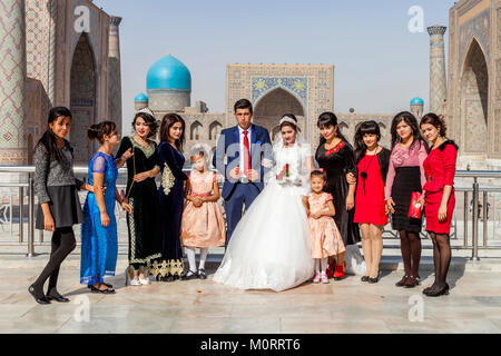 Una festa di nozze pone per le foto presso il Complesso Registan, Samarcanda, Uzbekistan Foto Stock