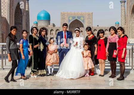 Una festa di nozze pone per le foto presso il Complesso Registan, Samarcanda, Uzbekistan Foto Stock