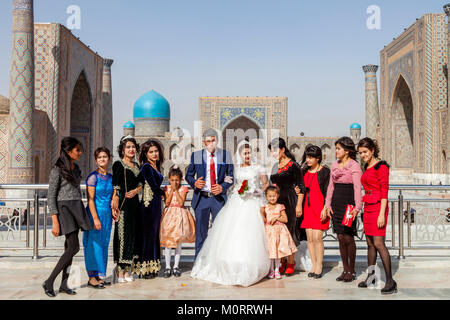 Una festa di nozze pone per le foto presso il Complesso Registan, Samarcanda, Uzbekistan Foto Stock