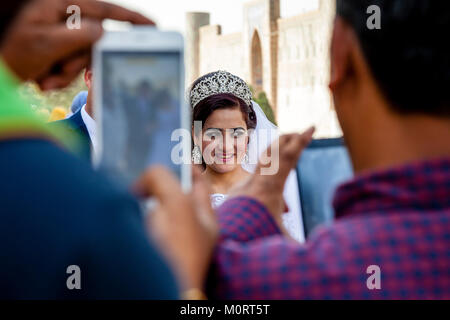 I turisti scattare delle foto di un 'Just Married " Coppia Giovane presso il Complesso Registan, Samarcanda, Uzbekistan Foto Stock
