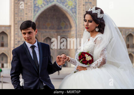 Un 'Just Married " Coppia Giovane posa per foto presso il Complesso Registan, Samarcanda, Uzbekistan Foto Stock