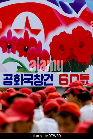 Corea del Nord la propaganda billboard in strada con Kimilsungia fiori e Nord bandiera coreana, Provincia di Pyongan, Pyongyang, Corea del Nord Foto Stock