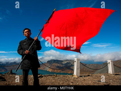 Nord coreano studente tenendo un grande bandiera rossa alla sommità del monte Paektu, Ryanggang Provincia, Mount Paektu, Corea del Nord Foto Stock