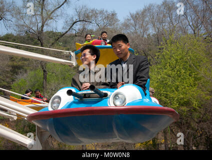 Nord Coreani divertirsi su un flying saucer attrazione di Taesongsan luna park, Provincia di Pyongan, Pyongyang, Corea del Nord Foto Stock