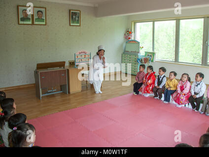 Nord coreano insegnante sotto i ritratti ufficiali del caro leader in un aula in Kim Jong suk scuola, Provincia di Pyongan, Pyongyang, Corea del Nord Foto Stock