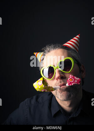 Il carnevale o compleanno ritratto concettuale di un uomo su uno sfondo scuro Foto Stock