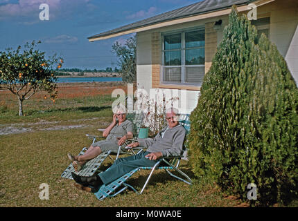 Vecchia coppia relax nel loro giardino sulla banana-tipo di sedia sdraio, USA, 1966 Foto Stock