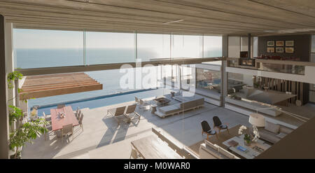 Vista in elevazione moderno, luxury home vetrina interno soggiorno e patio soleggiato con vista oceano Foto Stock