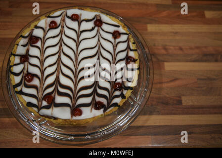 Fotografia di cibo di una casa fatta Bakewell tart torta con pasta frolla frangipane e mandorle con un pattern di cioccolato topping ghiacciato e ciliegie Foto Stock