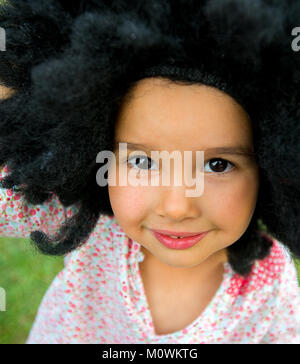 Ritratto di bambina indossa un grande nero e sorridente Foto Stock