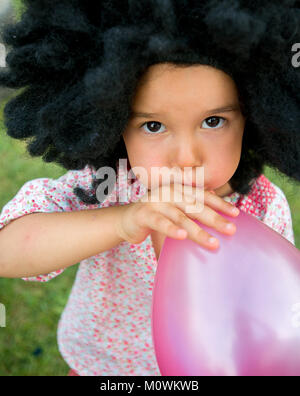 Ragazza che soffia su palloncino Foto Stock