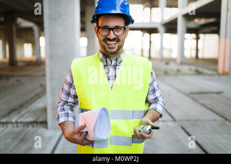 Architetto maschio con blueprint utilizzando un walkie-talkie Foto Stock