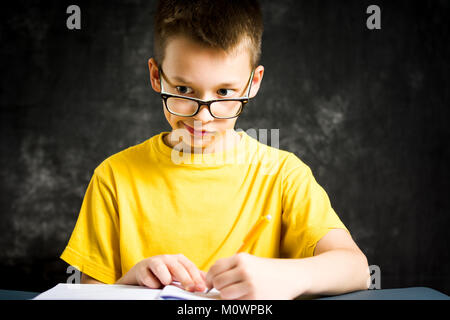 Ragazzo che facce mentre studiava per i compiti a casa Foto Stock