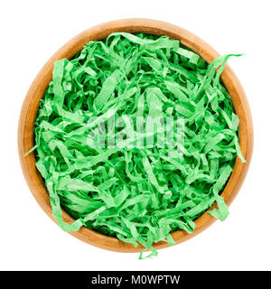 Libro verde erba di Pasqua nella ciotola di legno formando un nido. Colori vibranti e zigrinato cesto regalo shred per il riempimento e la decorazione. Foto Stock