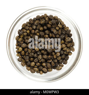 Essiccato nero semi di papaia in recipiente di vetro. Commestibile, con forte, sapore speziato, un sostituto per il pepe e per sconfiggere parassiti. Carica papaya. Foto macro. Foto Stock