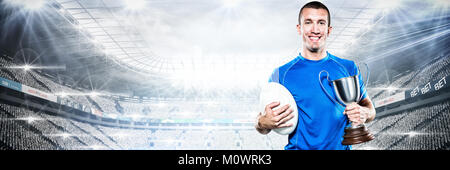 Immagine composita del ritratto di sorridere giocatore di rugby trofeo holding e la sfera Foto Stock