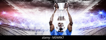 Immagine composita di felice sportivo guardando verso l'alto tenendo trophy Foto Stock