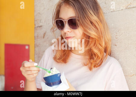 Europeo teenage girl in occhiali da sole mangia frutta gelato, close-up ritratto all'aperto Foto Stock