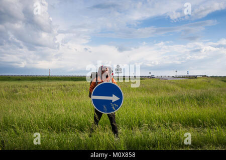 La Hitchhiker. L'uomo autostop su una strada di campagna nelle zone rurali del deserto del Nevada. Gli uomini la cattura di alcune auto. Foto Stock