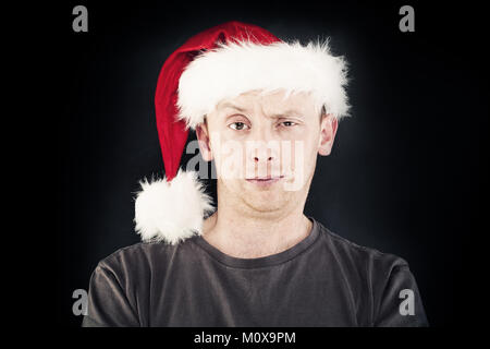 Natale Man. Uomo sorridente in Santa Hat su sfondo scuro Foto Stock