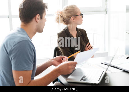 Vista laterale del giovane uomo cercando di parlare con il suo sconvolto offeso donna mentre essi lavorano a casa Foto Stock