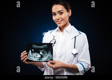 Giovani allegro medico con stetoscopio in azienda di scansione ad ultrasuoni di baby isolate su nero Foto Stock