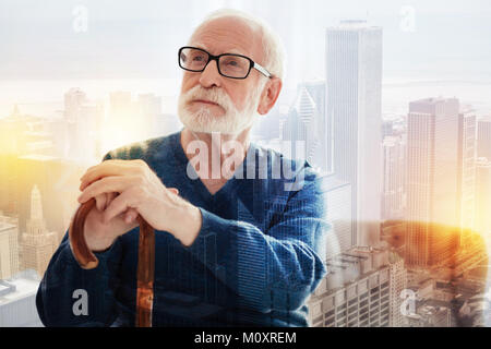 Senior uomo in bicchieri seduto con il suo bastone da passeggio Foto Stock