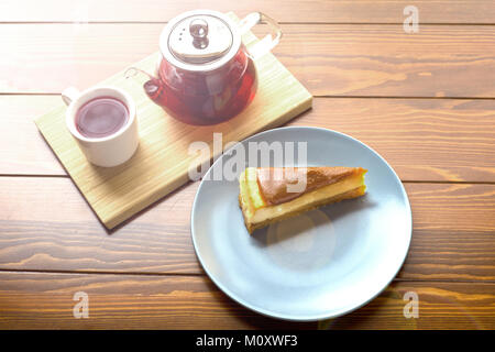 Teiera trasparente con tè caldo sul supporto a lungo con la Cheesecake al cioccolato Foto Stock
