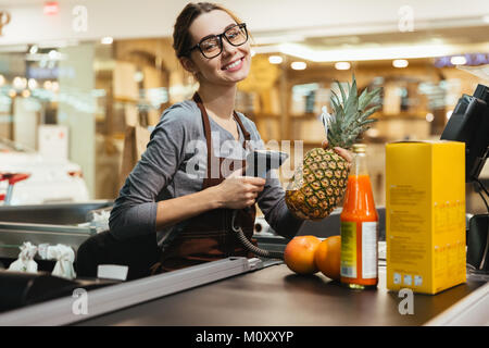 Felice cassiere femmina la scansione di articoli di generi alimentari al supermercato Foto Stock