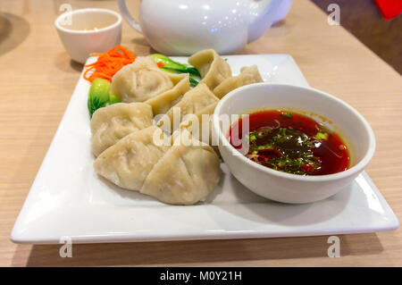 Tradizionale Cinese settentrionale bollito Jiaozi gnocco con piccante salsa di immersione. Questo piatto proviene da regioni del nord della Cina a Pechino e SHA Foto Stock