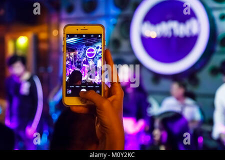 Donna che utilizza un telefono mobile (cellulare, smartphone, cellphone} di scattare una foto di una rock band in un night club, Saigon (Ho Chi Minh City), Vietnam Foto Stock