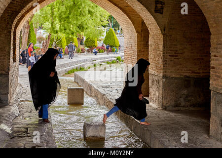 Isfahan, Iran - 24 Aprile 2017: Due ragazze iraniane vestito in un MUSULMANO nero chador sono attraversando il torrente di acqua sotto il ponte Allahverdi Khan, Foto Stock