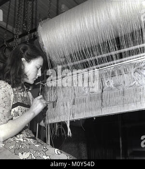 Degli anni Cinquanta, storico, giovani donne weaver lavorando su una tessitura di lino lomb, cancellazione di uno dei filetti, Irlanda del Nord. Foto Stock